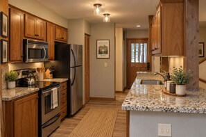 A kitchen with wooden cabinets, stainless steel appliances, granite countertops, and a built-in oven. - Black Butte Ranch House 045 (Black Butte Ranch)