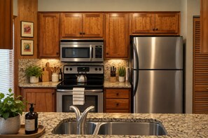 A kitchen with wooden cabinets, stainless steel appliances, granite countertops, and a double sink. - Black Butte Ranch House 045 (Black Butte Ranch)