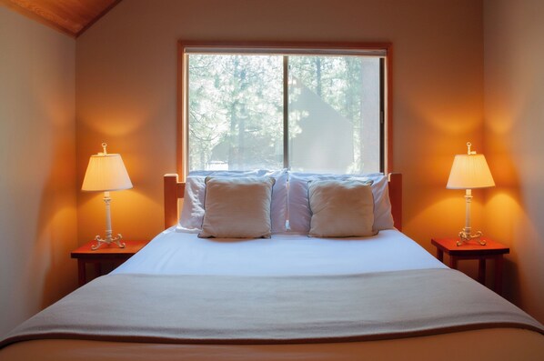 A neatly made bed with white bedding and two bedside lamps on wooden nightstands. - Black Butte Ranch House 049 (Black Butte Ranch)