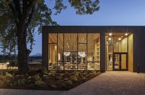 A modern building with large windows, a brick pathway, and a tree in the foreground. - Black Butte Ranch Country House 071 (Black Butte Ranch)
