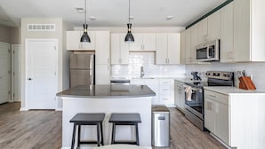 A modern kitchen with white cabinets, stainless steel appliances, and a central island with stools.