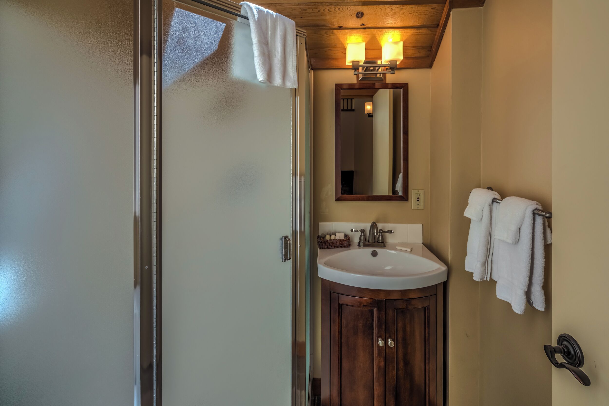 A bathroom with a wooden vanity, a white sink, and a mirror above it.