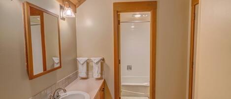 Une salle de bain avec un meuble-lavabo en bois, un évier, un miroir et deux appliques murales.