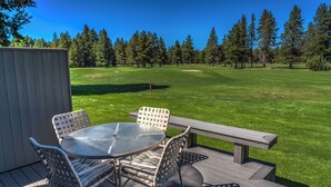 Una terraza con mesa y sillas, con vista a un campo de golf.