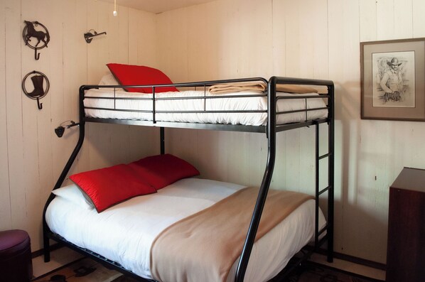 Un lit superposé avec un oreiller rouge et une couverture beige.