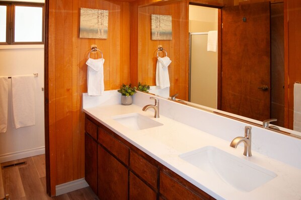 A bathroom with wooden paneling, a white sink, and a large mirror.