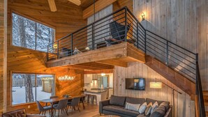 A spacious living area with a high ceiling, wooden walls, a balcony, and a staircase. - Black Butte Ranch Golf Home 174 (Black Butte Ranch)