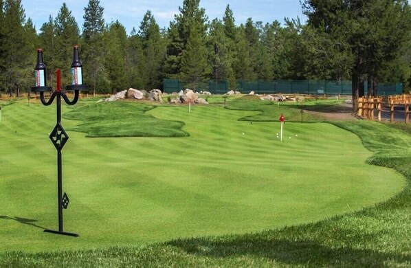 Un parcours de golf agrémenté d’un candélabre, d’une pelouse parfaitement entretenue et d’un pont en bois.