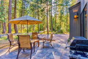 An outdoor patio with a table and chairs, a grill, and a large umbrella. - Black Butte Ranch Golf Home 212 (Black Butte Ranch)