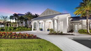 A modern building with a covered entrance, surrounded by well-maintained gardens and palm trees. - Landing | Incredible 1BD, Gym, Clubhouse (Nocatee)