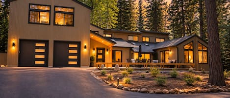 Une maison moderne à deux étages, dotée d’un garage, d’une terrasse avec mobilier d’extérieur et d’un jardin bien entretenu.