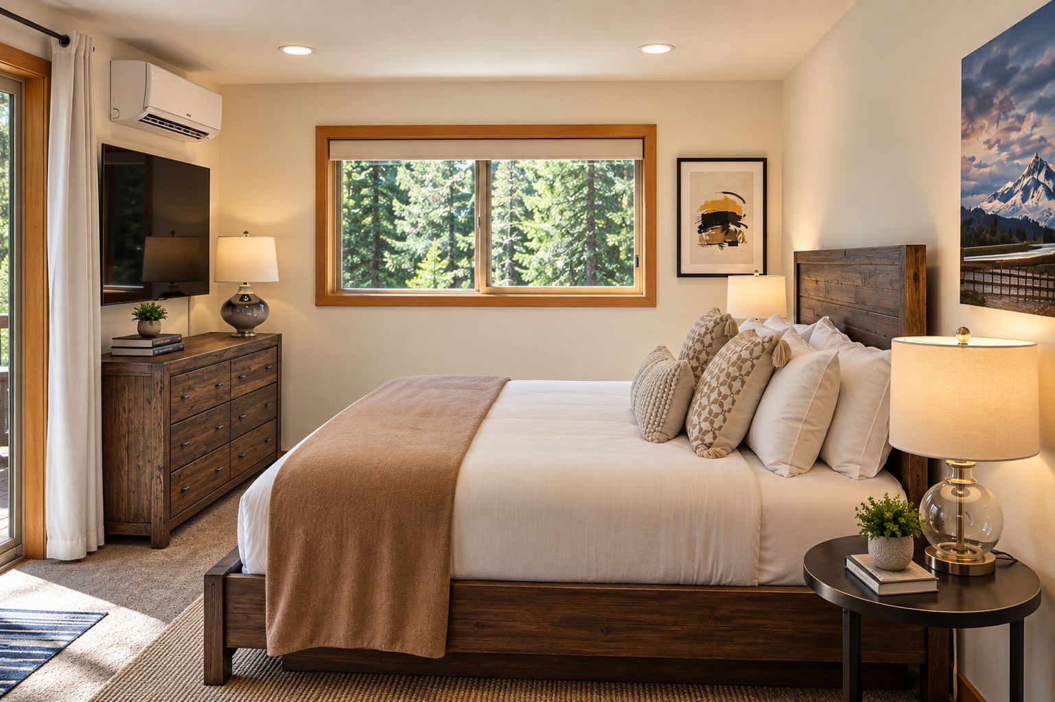 A bedroom with a large bed, a TV, a window with a view of trees, and a painting on the wall.
