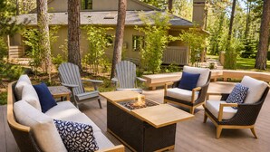 A deck with wicker furniture, a fire pit, and a view of a house. - Black Butte Ranch Glaze Meadow 006 (Black Butte Ranch)