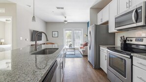 Eine moderne Küche mit Granit Arbeitsplatten, Edelstahlgeräten und Blick zum Wohnbereich.