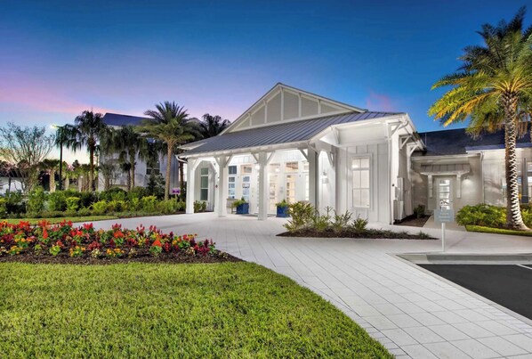 A modern building with a covered entrance, surrounded by well-maintained gardens and palm trees.