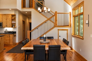 A spacious dining area with a wooden table and chairs, a staircase with wooden railings, and a kitchen with wooden cabinets. - Black Butte Ranch Glaze Meadow 141 (Black Butte Ranch)