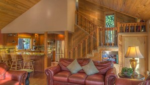 A spacious living area with a leather sofa, wooden staircase, and a kitchen in the background. - Black Butte Ranch Glaze Meadow 399 (Black Butte Ranch)