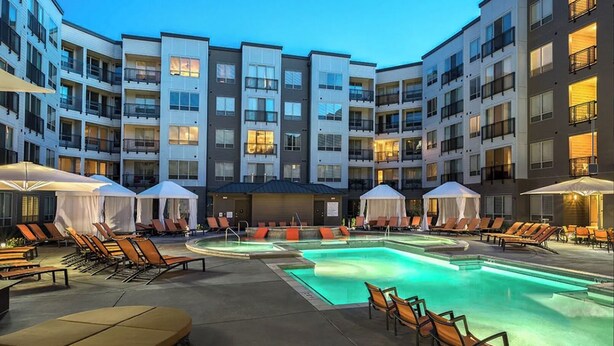 Une cour d’hôtel avec une piscine, des chaises longues et des parasols.