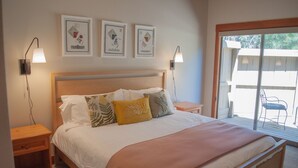 A bedroom with a wooden bed, white bedding, and three framed artworks on the wall. - Black Butte Ranch Lodge Room 016 (Black Butte Ranch)