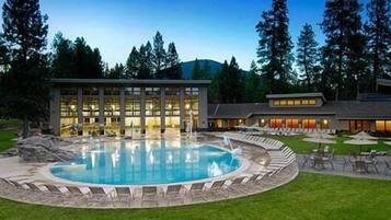 A hotel with a large pool, outdoor seating, and a building with multiple windows.