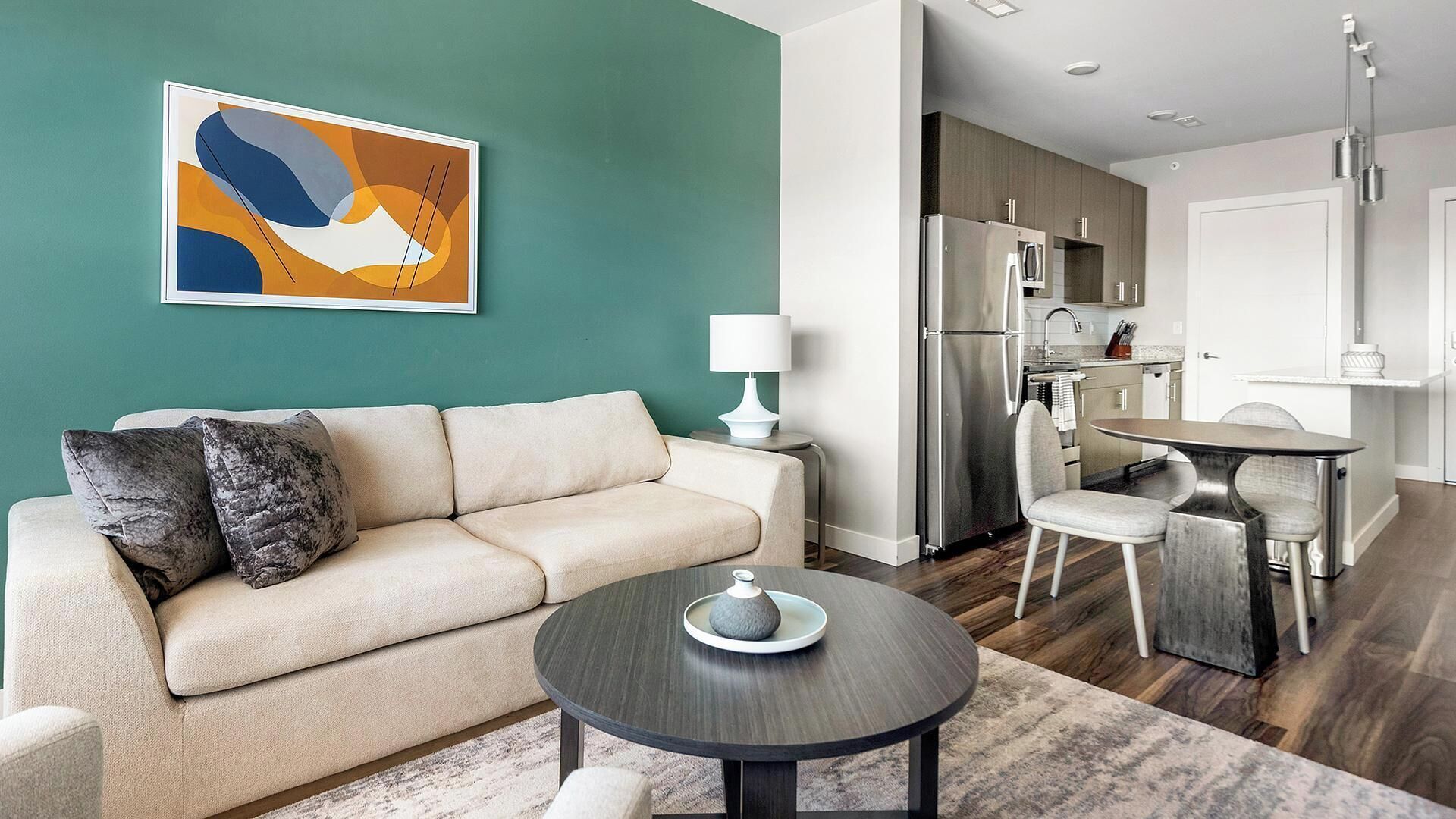 A modern living room with a sofa, a coffee table, and a painting on the wall.