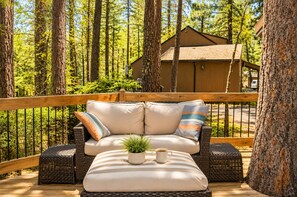 A deck with wicker furniture, a cushion, a small plant, and a cup.