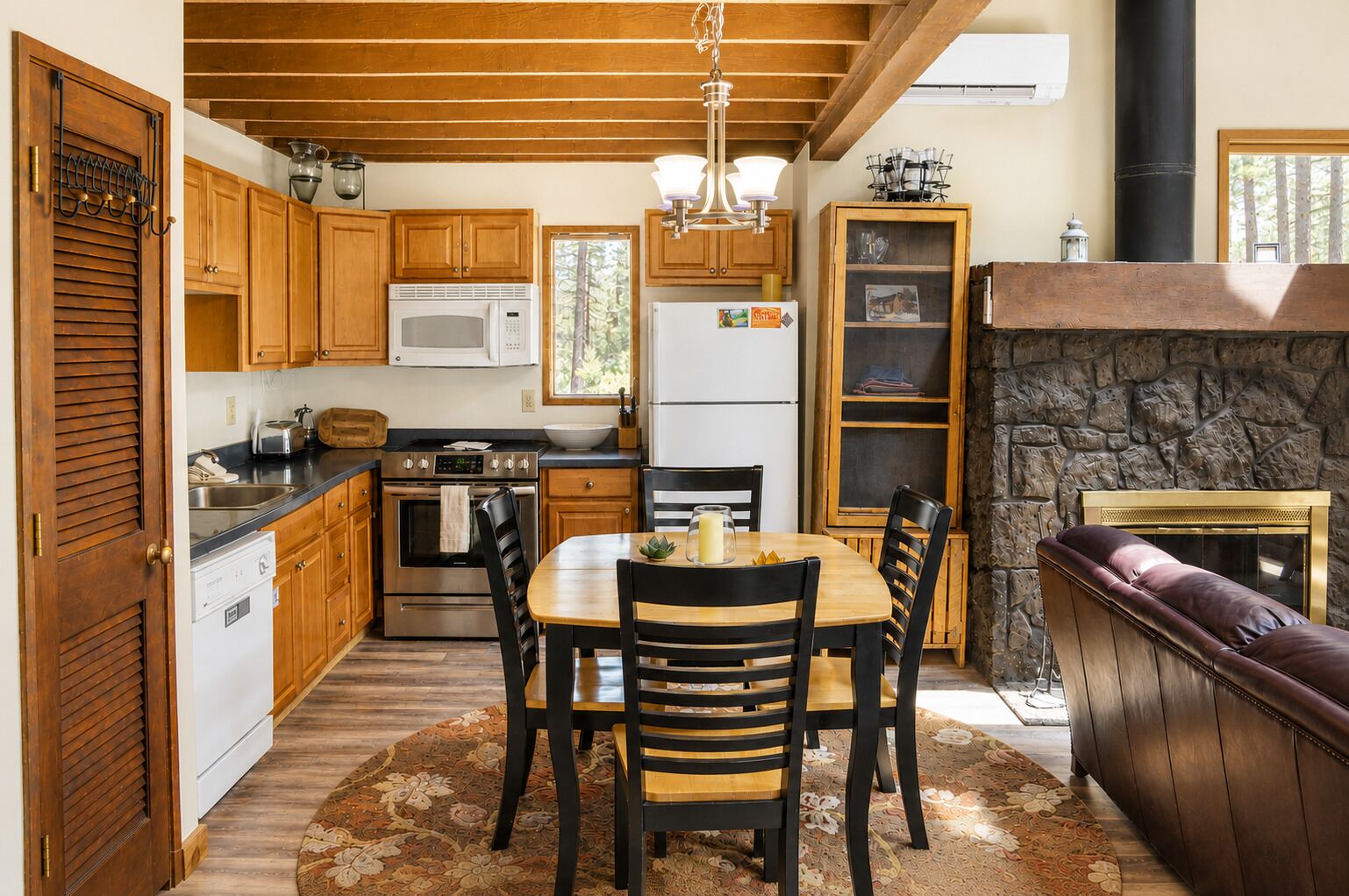 A kitchen with wooden cabinets, a microwave, a stove, and a dining area with a table and chairs.