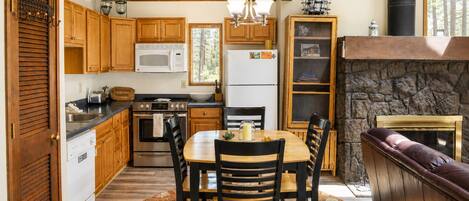 A kitchen with wooden cabinets, a microwave, a stove, and a dining area with a table and chairs.