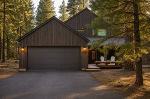 Ein zweistöckiges Holzhaus mit Garage, umgeben von Bäumen.