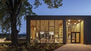 A modern building with large windows, a brick pathway, and a tree in the foreground. - Black Butte Ranch Ranch House 002 (Black Butte Ranch)