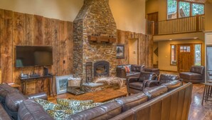 A spacious living room with a stone fireplace, leather sofas, and a flat-screen TV. - Black Butte Ranch Rock Ridge 004 (Black Butte Ranch)
