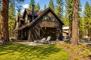 A wooden cabin with a porch, outdoor seating, and a chimney.