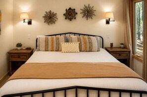 Un dormitorio con una cama, dos mesitas de noche, apliques de pared y decoración mural.