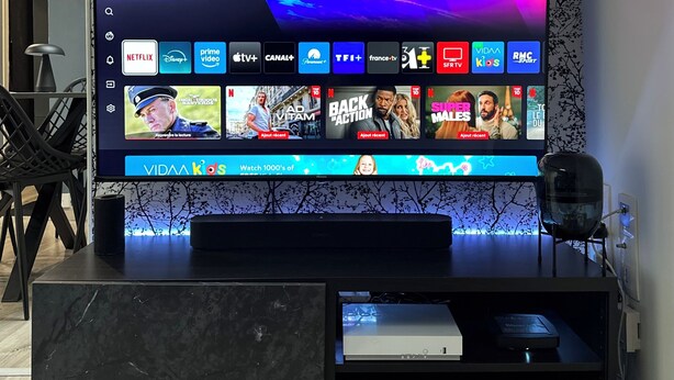 Un salon moderne avec un grand téléviseur à écran plat fixé sur une console en marbre noir.