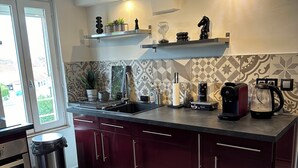 Une cuisine moderne dotée d’un îlot central, d’appareils électroménagers en acier inoxydable et d’un dosseret carrelé.
