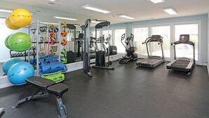 A gym with various exercise equipment, including treadmills, a weight machine, and exercise balls.
