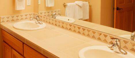A bathroom with two sinks, wooden cabinets, a large mirror, and a door.