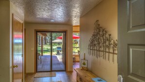 A hallway leading to a glass door with a view of an outdoor patio area.