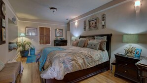 A bedroom with a large bed, a nightstand, a dresser, a chair, and a potted plant. - Renovated 1912 Home 2B/2B w/King&Queen fenced yard (Grants Pass)