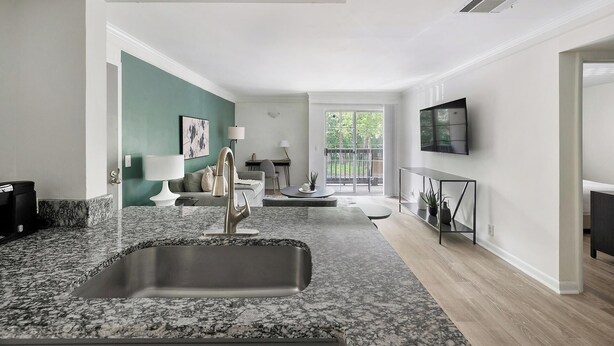 A modern kitchen with granite countertops, a stainless steel sink, and a dining area with a round table.