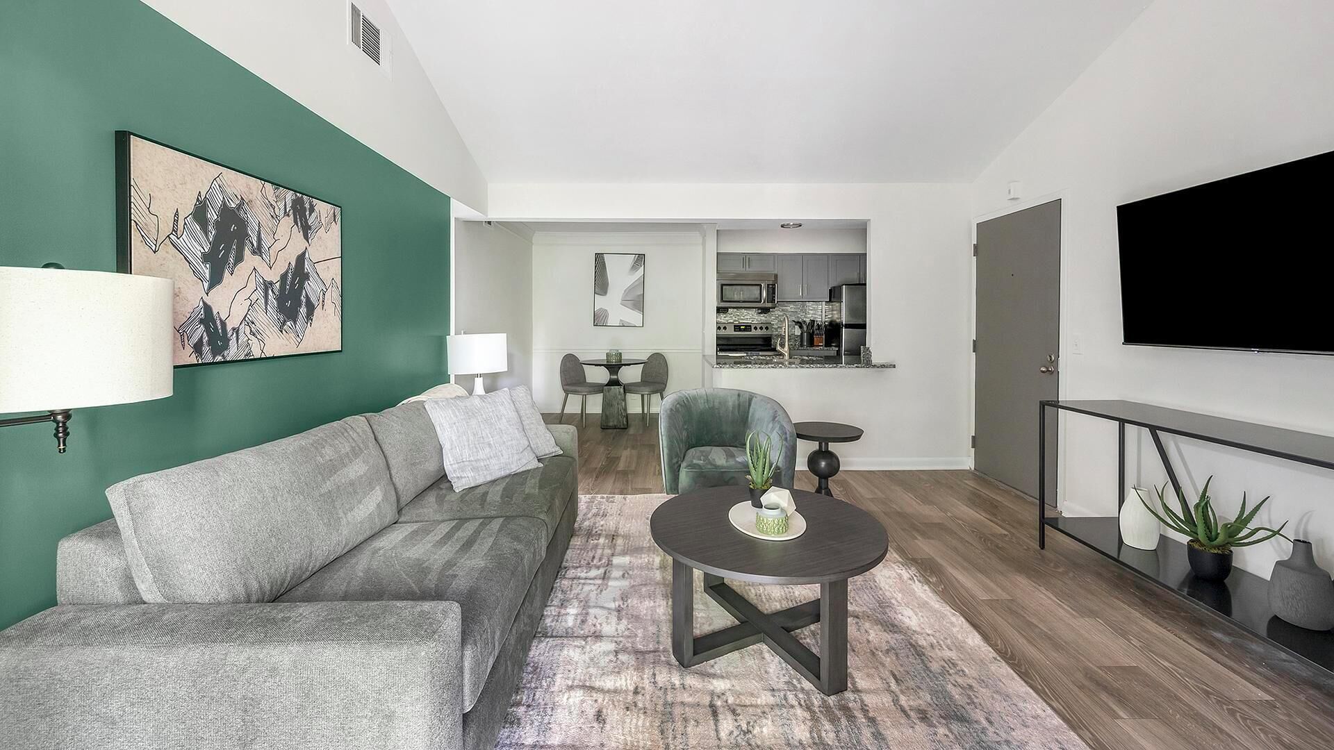 A modern living room with a grey sofa, a coffee table, and a TV.