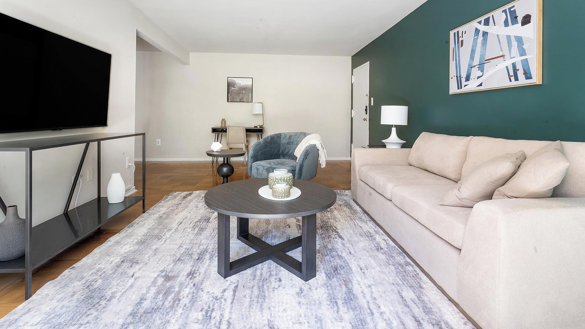 A living room with a sofa, a coffee table, a TV, and a painting on the wall.