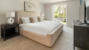 A bedroom with a large bed, two bedside tables, a TV, and a window with a view of the outside. - Landing | Stunning 2BD, Gym, Pool (Greenbelt)