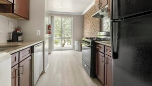 A kitchen with a stove, refrigerator, and a window overlooking a tree. - Landing | Stunning 2BD, Gym, Pool (Greenbelt)