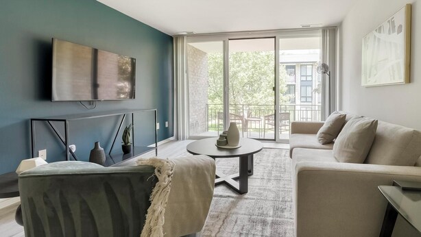 A modern living room with a sofa, a coffee table, and a TV mounted on the wall. - Landing | Stunning 2BD, Gym, Pool (Greenbelt)
