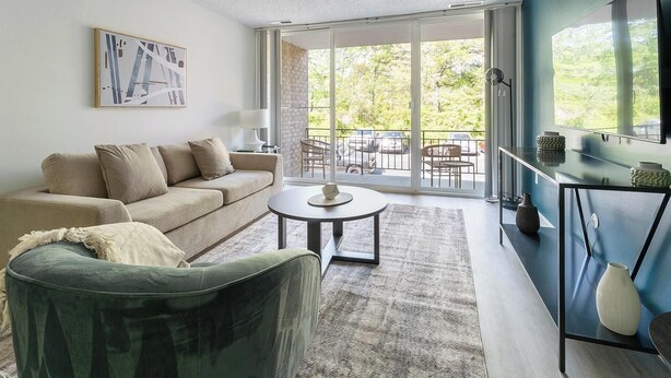 A modern living room with a sofa, a round coffee table, and a view of the outdoors through large sliding glass doors.