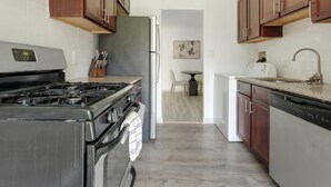 A kitchen with a gas stove, refrigerator, dishwasher, and wooden cabinets.