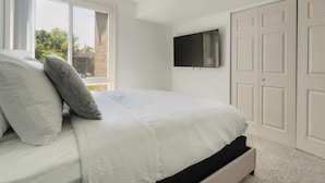 A bedroom with a bed, a TV mounted on the wall, and a closet.