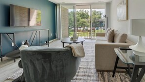 A modern living room with a grey sofa, a beige sofa, a round coffee table, and a TV mounted on the wall.