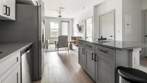 Et moderne køkken med grå skabe, et rustfrit stål køleskab og en stor køkkenø.